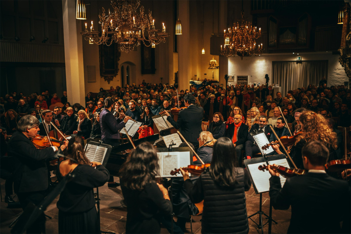 Ein Orchester spielt in einer vollbesetzten Kirche.