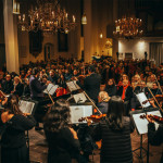 Ein Orchester spielt in einer vollbesetzten Kirche.