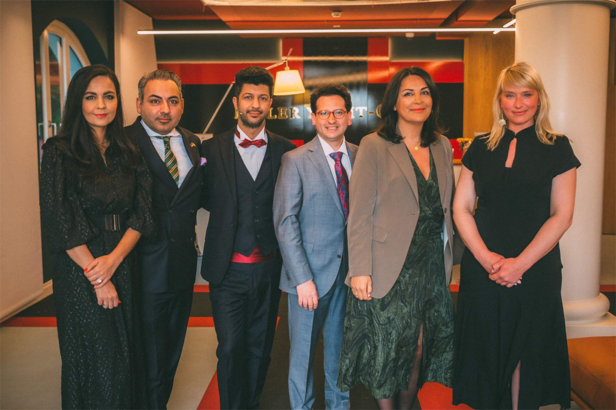 Bastian Mahmoodi steht mit fünf weiteren Personen für ein Gruppenfoto in einem Veranstaltungsraum.