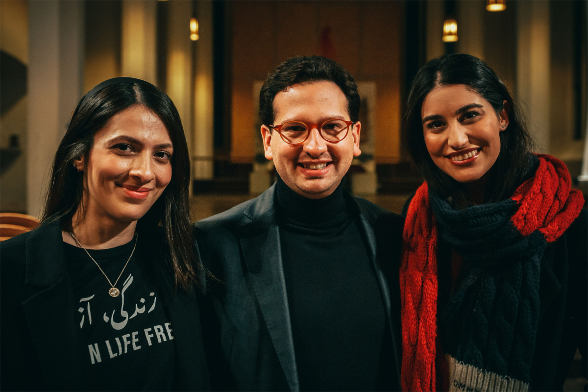 Bastian Mahmoodi steht mit zwei Frauen in einer Kirche und blickt in die Kamera.