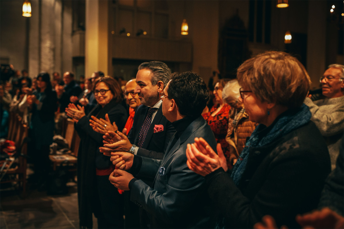 Publikum applaudiert bei einer Veranstaltung in einer Kirche.